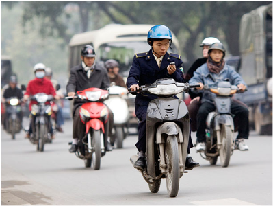 Hình (NPR): Một người vừa chạy xe gắn máy vừa dùng điện thoại di động tại Hà Nội.