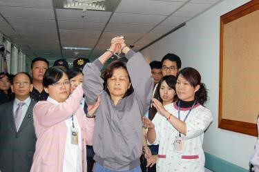 Hình 2: Bà Tô trị Phần đang giơ cao hai tay bị còng để phản đối khi bị đưa lên một xe cảnh sát đến cơ quan công tố để thẩm vấn (Ảnh chụp ngày 10/11/2008)