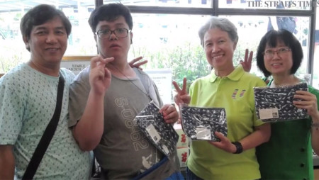 Bà Hà Tinh (thứ hai từ phải) trong buổi mua gây quỹ. Bà đã mua bóp với thiết kế của See Toh Sheng Jie (thứ hai từ trái) - Ảnh: STRAITSTIMES